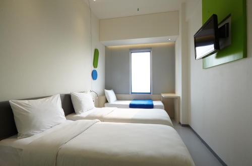 a hotel room with two beds and a television at POP! Hotel Festival Citylink in Bandung