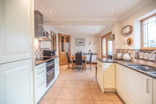 a kitchen with white cabinets and a table at 5 Toller Close, Orford in Orford