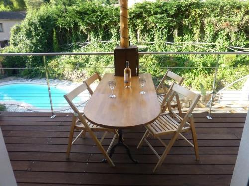 une table et des chaises en bois sur une terrasse avec une piscine dans l'établissement Appartement dans superbe Villa, à La Croix-Valmer