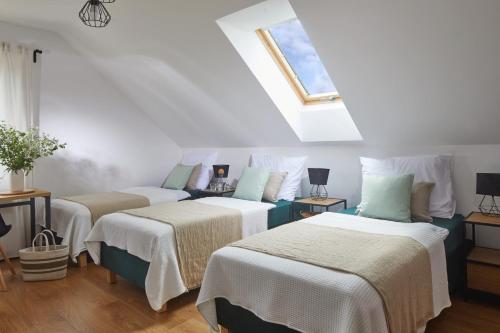 a attic room with three beds with white sheets at Szczęśliwe Siedlisko in Rumy