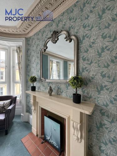 a living room with a fireplace and a mirror at Cross Wynd Apartment in Hawick