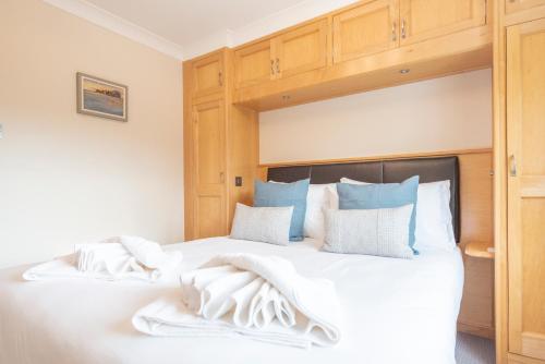 a bedroom with a bed with white sheets and blue pillows at 5 Toller Close, Orford in Orford
