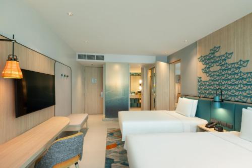 a hotel room with two beds and a desk at Holiday Inn Pattaya by IHG in Pattaya Central
