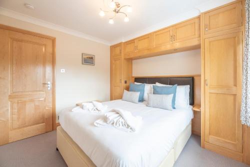 a bedroom with a large white bed with wooden cabinets at 5 Toller Close, Orford in Orford