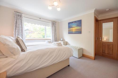 a bedroom with a large white bed with a window at 5 Toller Close, Orford in Orford