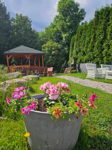 a large pot of flowers in a garden with a gazebo at Centrum Spokoju - Domki w Karkonoszach in Podgórzyn
