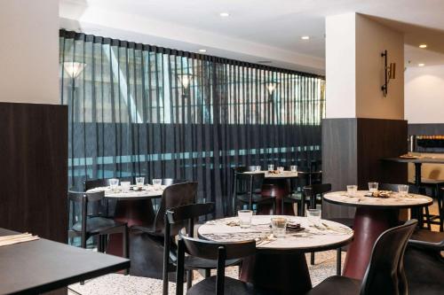 restauracja ze stołami i krzesłami oraz oknem w obiekcie The Capitol Hotel Sydney w mieście Sydney