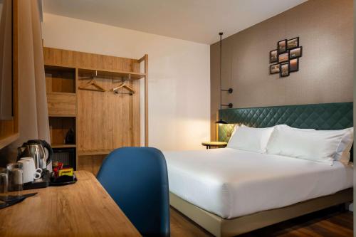 a bedroom with a large bed and a blue chair at Hilton Garden Inn Milan Malpensa in Somma Lombardo