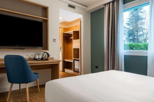 a bedroom with a bed and a desk and a television at Hilton Garden Inn Milan Malpensa in Somma Lombardo