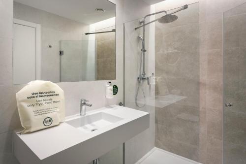 uma casa de banho branca com um lavatório e um chuveiro em B&B HOTEL Écija em Écija