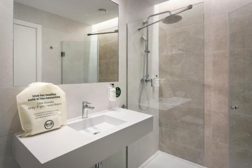 a white bathroom with a sink and a shower at B&B HOTEL Écija in Écija