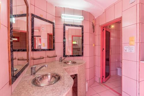 a pink bathroom with two sinks and two mirrors at Paco's Resort Barbie House in Oziás