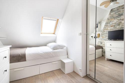 une chambre blanche avec un lit et une télévision dans l'établissement Appartement lumineux et cosy Gare du Nord - Opéra, à Paris