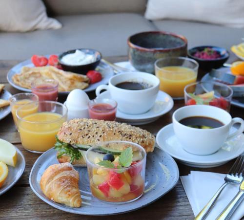 a table with plates of breakfast foods and cups of coffee at Hotell Slottsgatan in Oskarshamn