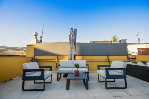 a patio with three chairs and an umbrella on a roof at Attico Centro con terrazza e jacuzzi e parcheggio privati in Genova