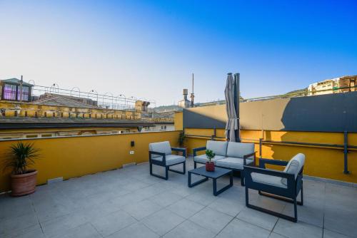 a patio with chairs and a table on a roof at Attico Centro con terrazza e jacuzzi e parcheggio privati in Genova