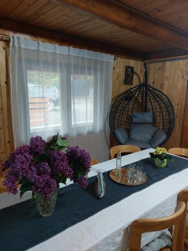 a table with purple flowers in a room at Cabana Stînă - Duplex Montan in Topliţa