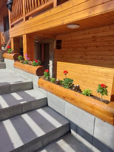 a building with a wooden retaining wall with flowers on it at Cabana Stînă - Duplex Montan in Topliţa