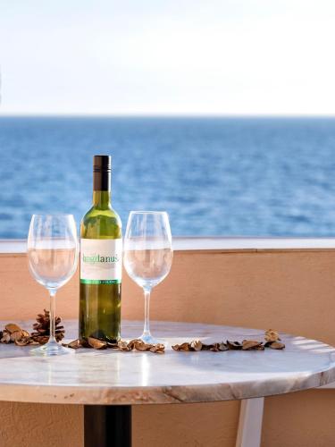 a bottle of wine sitting on a table with two glasses at Apartments Spila Beach in Ivan Dolac