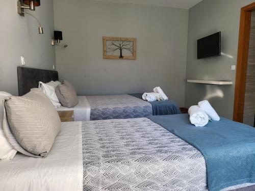 a hotel room with three beds and a television at Leao de Ouro in Matosinhos