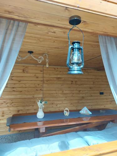 a light hanging over a bed in a room with wooden walls at Cabana Stînă - Duplex Montan in Topliţa