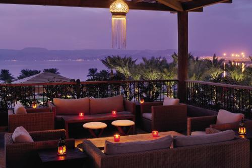 a restaurant with couches and tables and a view of the ocean at Mövenpick Resort & Spa Tala Bay Aqaba in Aqaba