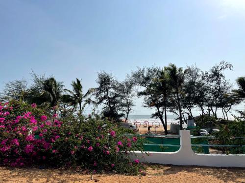 a view of the beach from a resort with pink flowers at Papilio Beach Front Cottages-TBV in Old Goa