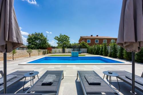 a swimming pool with two lounge chairs and umbrellas at Villa Alves with Private Pool in Tar