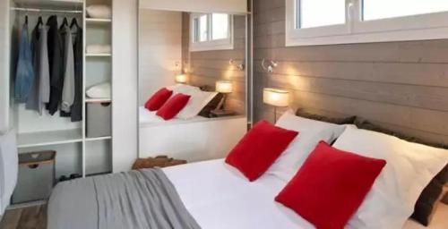 um quarto com uma cama branca e almofadas vermelhas em Chalet 3 étoiles - Piscine - eebc0a em Pluherlin