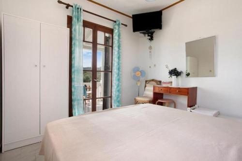 a bedroom with a bed and a desk and a window at Areti Orfeas Studios in Vasilikos