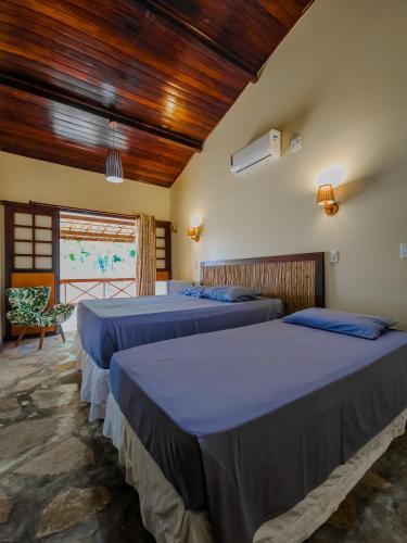two beds in a room with wooden ceilings at Sunset Beach Villas in Taíba