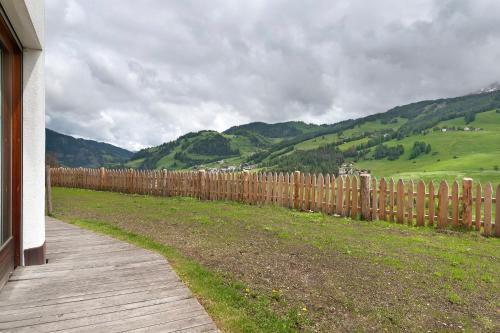 a wooden fence in front of a field with mountains at Paracia App Cir in Badia