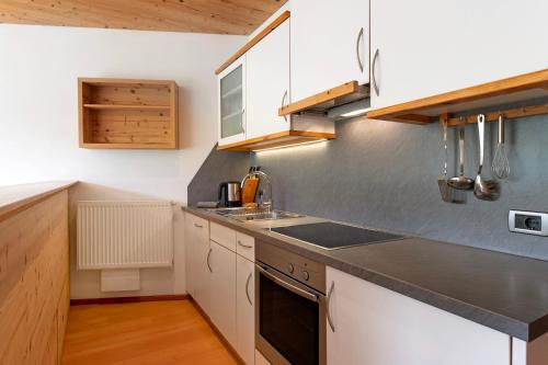 a kitchen with white cabinets and a sink at Paracia App Cir in Badia