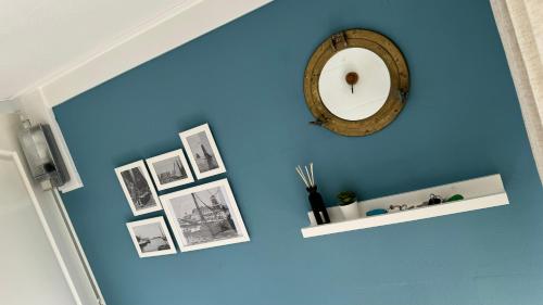 a blue wall with a clock and pictures on it at Woonboot 4 Harderwijk in Harderwijk