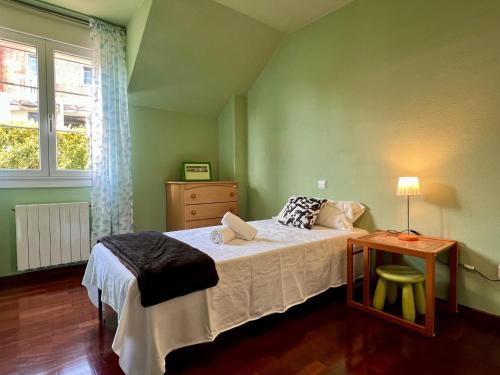a bedroom with a bed and a table and a window at Casa Mirador del Pas - Monabri in Boó de Piélagos
