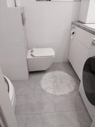 a bathroom with a white toilet and a white rug at Apartament na Sadowej in Sanok