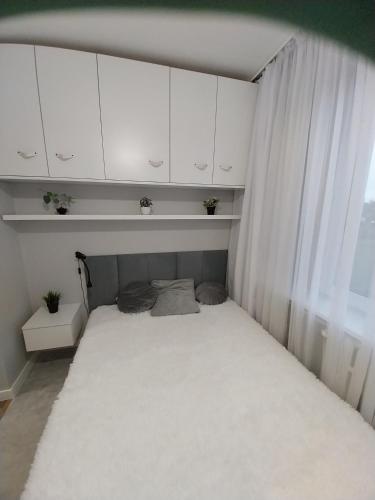 a small bed in a room with white cabinets at Apartament na Sadowej in Sanok