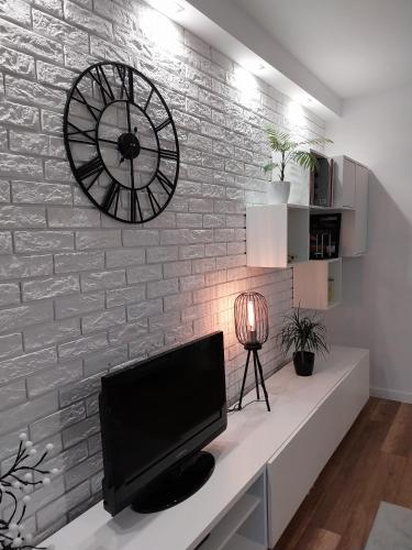 a large clock on a brick wall with a television at Apartament na Sadowej in Sanok