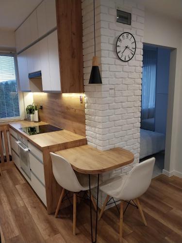 a kitchen with a table and a clock on a brick wall at Apartament na Sadowej in Sanok