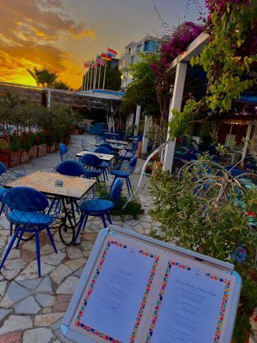 a group of tables and chairs with a sign at Bougainvill Sunset Villa in Sarandë