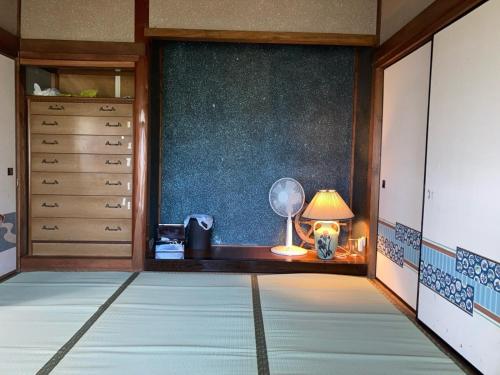 um quarto com um quarto com uma ventoinha e um candeeiro em しまなみゲストハウス南風荘 em Imabari