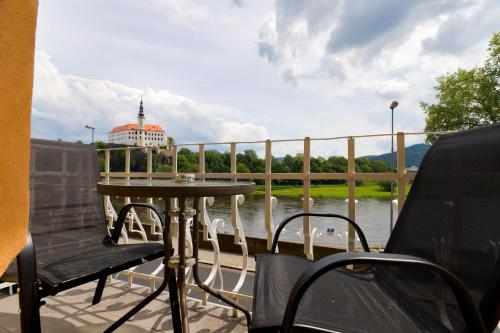 a table and chairs on a deck with a view of the water at Apartmány Děčín in Děčín