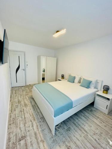 a white bedroom with a large white bed with blue pillows at Apartament Olimp in Olimp