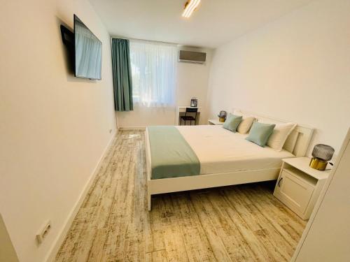 a white bedroom with a bed and a window at Apartament Olimp in Olimp