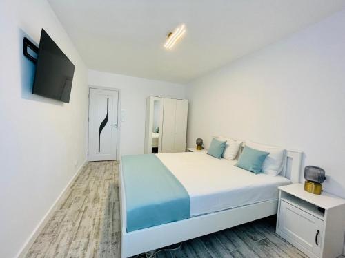 a white bedroom with a large bed and a television at Apartament Olimp in Olimp