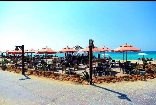 a group of tables and chairs with umbrellas on the beach at قرية نيس in Dawwār Muşādif Yūnus