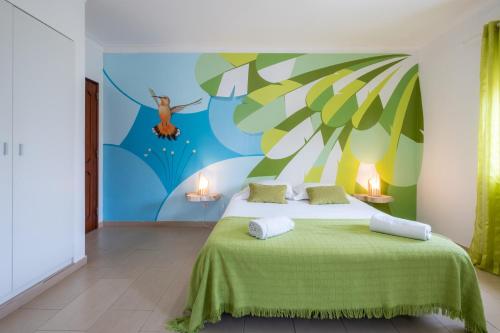 a bedroom with a bed with a painting on the wall at West Side Guesthouse in Peniche