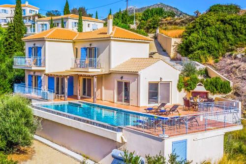 a house with a swimming pool on a hill at Villa Louloudia in Ratzaklíon