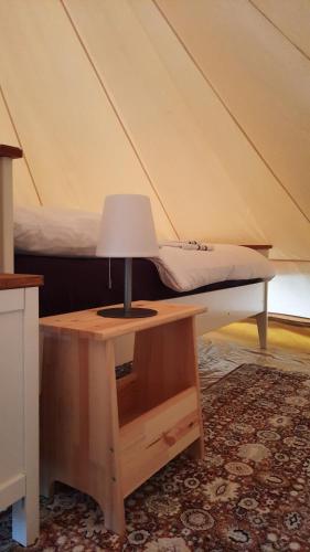 una lámpara en un escritorio junto a una cama en Glamping im 5 m Zelt auf dem Bauernhof en Walsrode