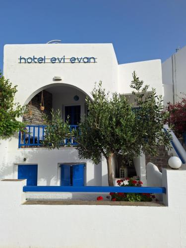 biały budynek z niebieskimi drzwiami i drzewami z przodu w obiekcie Εvi Evan Hotel w mieście Galissas